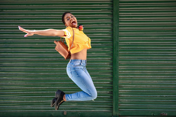 Young black woman jumping on blinds background.