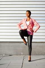 Black woman, model of fashion, standing on urban wall
