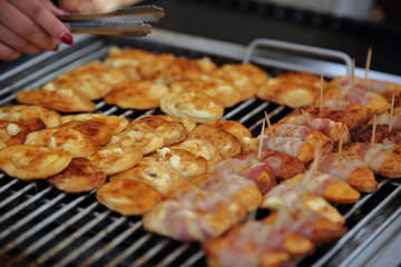 Traditional sheep cheese from tatra mountains in Poland, called oscypek in polish, grilled on grill, female hand with pliers, close up
