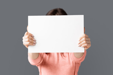 Woman holding empty advertising board in front of her face