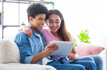 Fototapeta premium Cheerful teenagers using digital tablet together while sitting at home