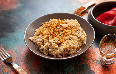 Traditional for Turkish, Greek and Iranian cuisine, a dish called Keskek. Served with pickled red peppers, butter and paprika powder. Close-up, copper background, copyspace