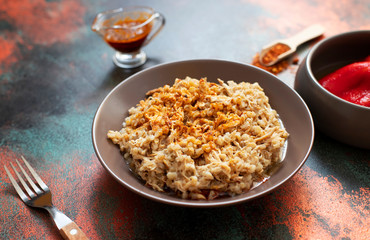 Traditional for Turkish, Greek and Iranian cuisine, a dish called Keskek. Served with pickled red peppers, butter and paprika powder. Close-up, copper background, copyspace