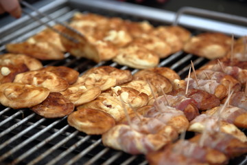 Traditional Polish mountain cheese from Tatra mountains, called oscypek,  while grilled, close up, hand with kitchen equipment touching one 