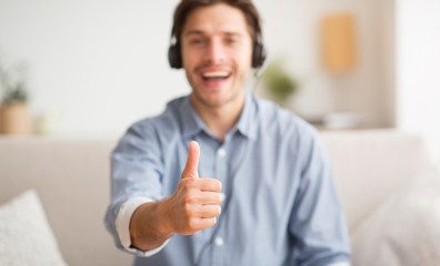 Excited Man Gesturing Thumbs-Up Listening To Music Via Wireless Headphones