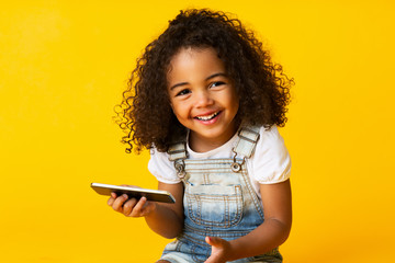 Cute african american girl holding cellphone and smiling