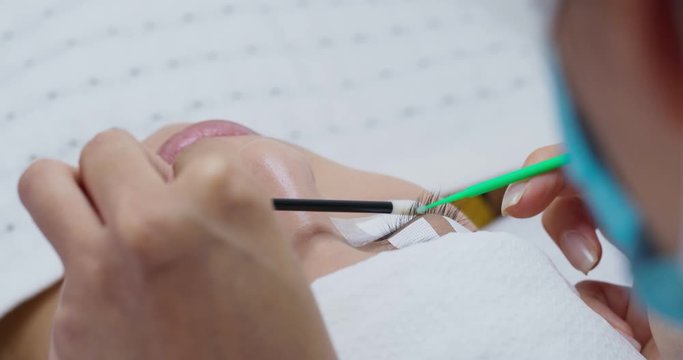 Beauty professional procedures eyelash extension on woman eyes