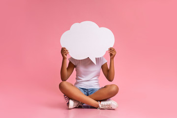 Teenage girl sitting with crossed legs and holding speech bubble