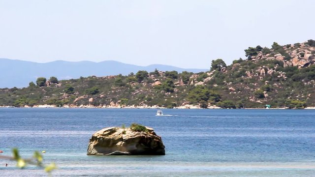 Idyllic coast, rock with trees by the sea and a rock alone in the middle, Halkidiki Greece