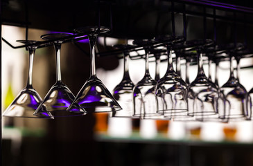 Glasses for martini and wine hang over a counter in restaurant