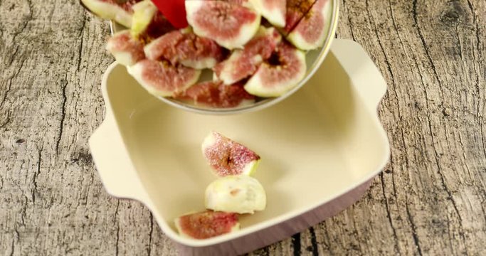 Putting wedged figs, sliced lemon and sugar in ceramic pot to make compote