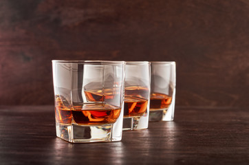 Glass of whiskey on a wooden tableThree glasses of whiskey on a wooden table