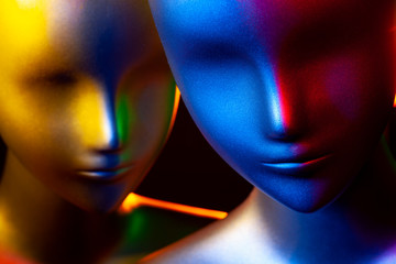 Two mannequin heads illuminated by various colors