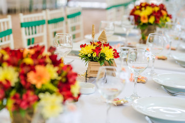 Fototapeta na wymiar Wedding table set up decoration made of red and yellow fresh flowers. Rustic/ garden wedding decoration