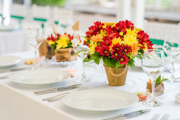 Wedding table set up decoration made of red and yellow fresh flowers. Rustic/ garden wedding decoration