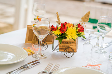 Wedding table set up decoration made of red and yellow fresh flowers. Rustic/ garden wedding decoration