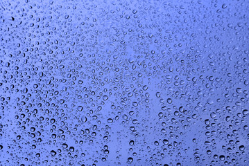 Water drops on glass, blue natural background