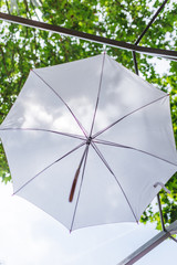 Swinging outdoor white umbrella decoration and green leaves of trees