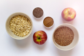 Healthy breakfast - apples, grains , oats, buckwheat, cinnamon, chia seeds on white background.