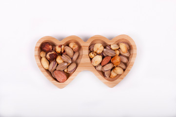 Nuts, almond pistachios in a heartshpe bowl with whitebackground