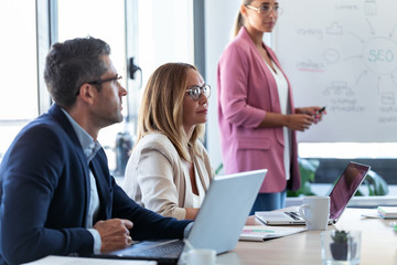 Concentrated business team listening they partners and working with laptop on coworking space.