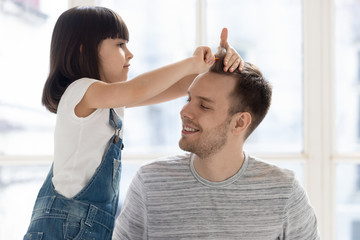 Cute funny kid daughter playing with father brushing hair