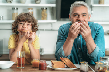 Happy father and kid eating breakfast at kitchen