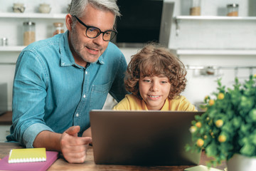 Fototapeta na wymiar Father and kid looking on laptop display