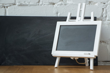 Close-up of a miniature chalk board on the background of a large chalk board with chalk stains, selective focus