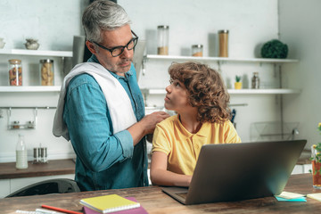 Obraz premium Father standing near little kid with laptop computer