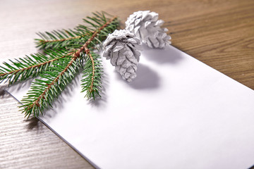 empty paper  with fir branches and cones on the wooden background