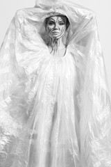 Fototapeta na wymiar Model in a raincoat made of cellophane and in creative make-up
