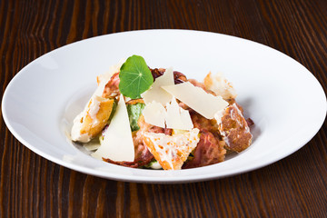 Cesar salad with chicken and parmesan on wooden table
