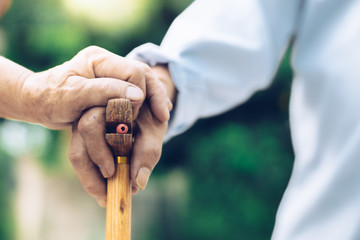 Close up of elderly hands in wrinkles holding walking stick.elderly old man with walking stick stand on footpath sidewalk crossing.