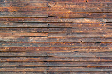 Close-up of a  brown horizontal wooden  wall  painted a very long time and the paint peeled off.  Brown texture background