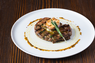 Beef steak on white plate, decorated with garlic and rosemary