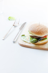 Burger mit Rindfleisch, Käse und frischem Salat auf einem Holzbrett serviert