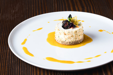 Vanilla ice cream, decorated with nuts flakes, blackberry, mint and flower on white plate
