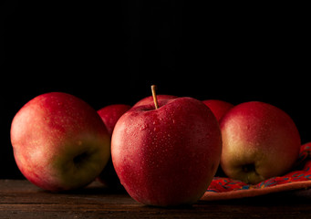 fresh red apple with droplets of water against black background with space for text