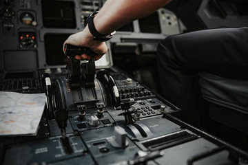 Male arm pushing throttle in cockpit of aiplane