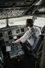 Caucasian adult man in uniform piloting perfectly modern airplane - obrazy, fototapety, plakaty
