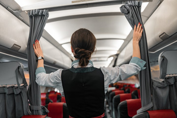 Caucasian female flight attendant welcoming passengers on board