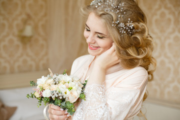 Pretty young girl. Blonde woman with luxurious long curly hair. Boudoir morning of the bride. Taking wedding bouquet in her hands. Touching her neck