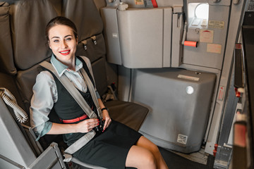 Pretty flight attendant seating belt in airplane