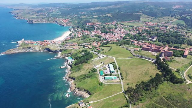 Aerial panoramic view of summer landscape overlooking small Spanish town of Comillas on coast of Cantabrian Sea