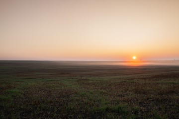 Fototapeta na wymiar Sunrise on the empty field in the morning mist.