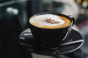 close up modern hot black coffee the cappuccino on dark background with coffee bubble foam pattern and texture in black cup looking and feel so delicious on glasses table in coffee shop.