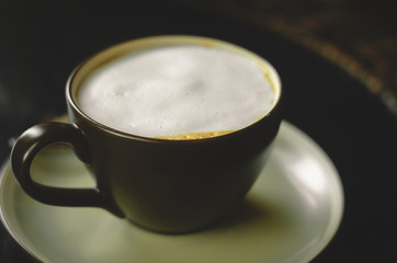 close up modern hot black coffee the cappuccino on dark background with coffee bubble foam pattern and texture in black cup looking and feel so delicious on glasses table in coffee shop.