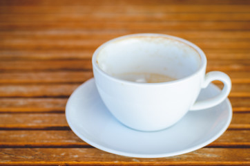 close up modern hot black coffee the cappuccino on wood background with coffee bubble foam pattern and texture in empty white cup looking and feel so delicious on glasses table in coffee shop.