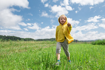 Naklejka na ściany i meble little a boy in yellow clothes runs through a green meadow